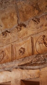 Vertical view of an ornate preserved ceiling in Pompeii with classical reliefs, decorative panels, and weathered Roman interior art inside the ancient archaeological site.