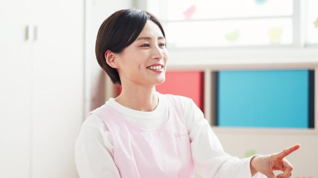 幼稚園の教室で子供に優しく語りかける保育士の女性