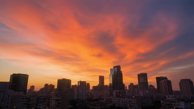 Wide Cinematic Shot of Urban Skyline at Golden Hour with Dramatic Sunset Clouds Lit in Orange and Gold