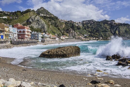 Sea surf in front of the promenade with Taormina on the hill, Giardini-Naxos, east coast, Sicily, Italy