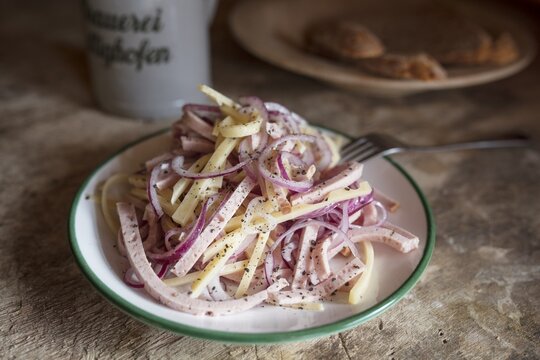 Swiss sausage salad, served in a plate on a wooden table, Bavaria, Germany