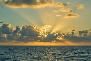 Golden sun rays breaking through clouds over ocean © Alessandro