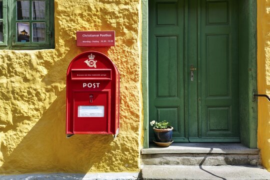 Post office, fa&ccedil;ade detail, red mailbox with post horn and crown, green wooden door, yellow wall, Christians&oslash;, Christians&ouml;, Ertholmene, Pea Islands, Bornholm, Baltic Sea, Denmark