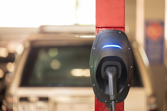 EV charging and electric car, Electric car charging station for charge EV battery, Plug for vehicle with electric engine, EV charger clean energy, Charging point at car parking lot.