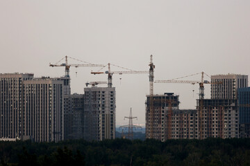 Fototapeta premium Modern residential apartment buildings under construction with cranes