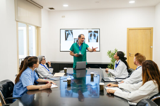 Doctors and nurses gathering for a hospital briefing, reviewing x rays and discussing patient care and health information