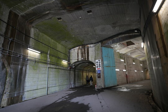 Tourists walking inside a massive concrete underground tunnel station.
