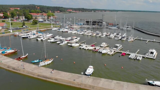 Drone footage showcasing the bustling Nida harbor and marina with various yachts and boats docked, located on the Curonian Spit in Neringa, Lithuania.