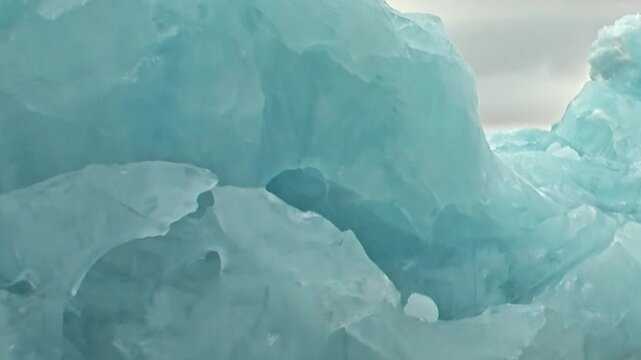 Breathtaking spectacle of colossal sapphire ice sculpted by nature in remote Arctic Ocean. Experience extreme travel exploring these majestic formations during daytime voyage under muted skies.