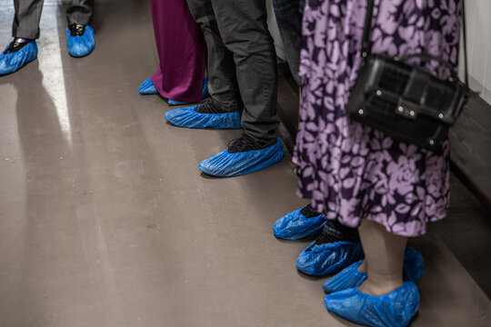 Cropped view of people wearing blue protective shoe covers on a clean factory floor during brewery or food production visit, with copy space