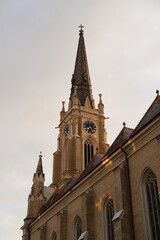 Fototapeta premium Church tower and steeple with clock, gothic brick architecture, daylight sky, ornate exterior of historic religious building