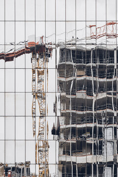 a crane reflection wavers across the glass facade, merging construction, urban building site architecture and city exterior lines into distortion