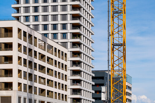 beside the building facade, a construction crane anchors an urban site where city development, architecture and windows repeat in grid lines