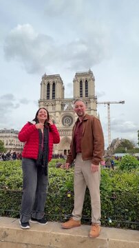 Joyful couple having fun and jumping in slow motion, celebrating their vacation together in front of the historic Notre Dame Cathedral, a famous landmark in Paris, France