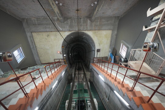 Symmetrical wide perspective of steep underground cable car tunnel track.