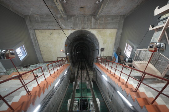 Symmetrical wide perspective of steep underground cable car tunnel track.