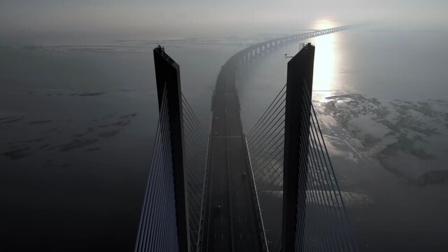 Aerial drone shot of Vasco da Gama bridge during sunrise in Lisbon Portugal over Tagus river.