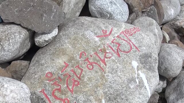 Gray stones bearing vibrant red traditional script, likely sacred blessings, stand as a testament to deep cultural heritage and timeless spirituality on Lake Khuvsgul's serene shores in Mongolia.