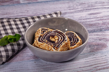 Sesame coated sweet roll with nuts in grey ceramic bowl on rustic wooden table with mint leaf © Andrei Starostin
