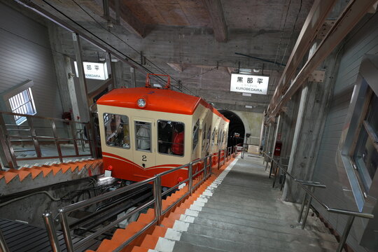 An orange alpine cable car parked at Kurobedaira Station platform.