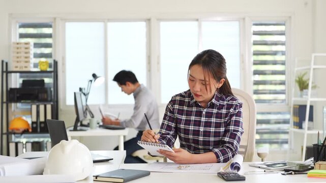 Professional construction engineer checking details on blueprint in construction site office.