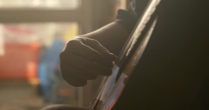 close-up hand plucking the strings, a classical guitar, fingers positioned delicately over the strings with visible motion blur suggesting active playing, dramatic