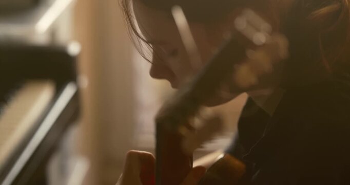 Cinematic close-up of a guitar neck and piano. Profile portrait of a teenage girl practicing music at home, musical education, harmony, and artistic lifestyle