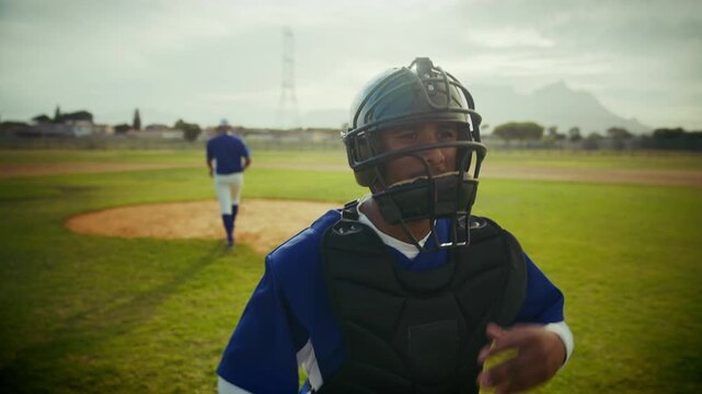 A focused catcher in full gear watches intently from home plate. A pitcher stands ready on the mound in the distance, anticipating the next play in the game.