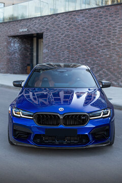 Blue BMW M5 performance sedan near modern wall. Premium sports car with aggressive styling and urban atmosphere. Concept of speed, prestige, success, and luxury lifestyle.