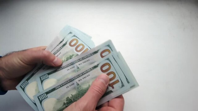 Close up view of hands counting large stack of hundred dollar bills in american currency.