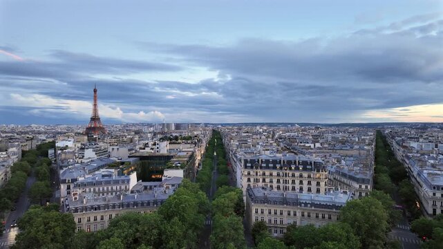 Aerial view of Eiffel tower in Paris France at twilight with beautiful city architecture and tree lined streets during summer evening.