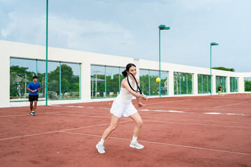 Obraz premium Asian sportsman and woman playing tennis match on outdoor clay court.