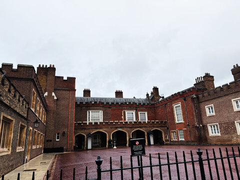 Historic redbrick Friary Court palace courtyard in London, UK with overcast sky and wrought iron gate