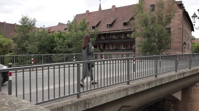 Woman walking on a bridge with historic buildings and a car passing by