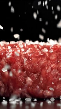 The cook sprinkles salt on the meat burger. Filmed on a high-speed camera at 1000 fps. High quality FullHD footage