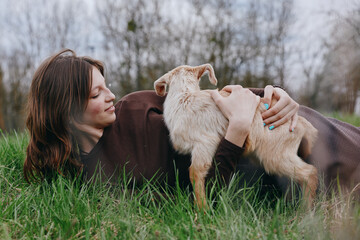 Fototapeta premium Young woman lying on grass beside gentle goats in a meadow, capturing bonding, care, and joy in a natural outdoor setting with soft daylight and a relaxed mood.