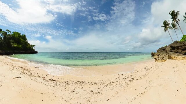 Tropical landscape of ocean waves crashing on sandy beach in Carabao Island in Romblon, Philippines.