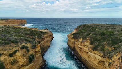 Fototapeta premium Thunder Cave and Mutton Bird Island, Great Ocean Road, Port Campbell, Victoria, Australia: 4K aerial drone view of sea cave, cliffs, coastline and ocean waves