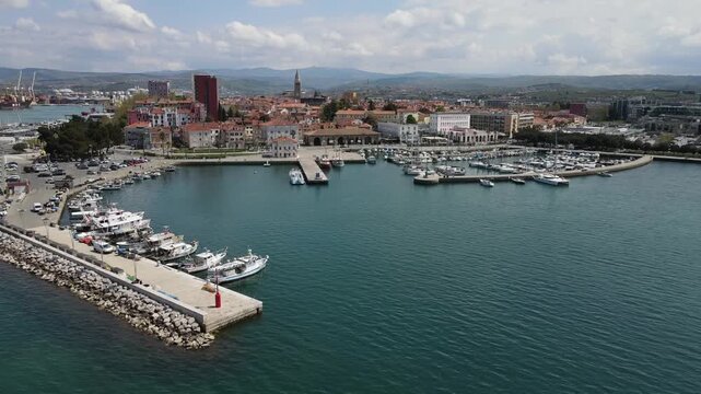 Curving aerial reveal of Koper marina and bell tower