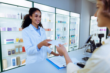 Fototapeta premium Professional pharmacist processing customer paperwork and prescription at pharmacy checkout counter