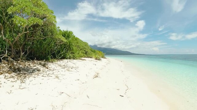 Isolated Island with white sand beach and waves. Mantigue Island. Blue sky and clouds. Camiguin, Philippines.