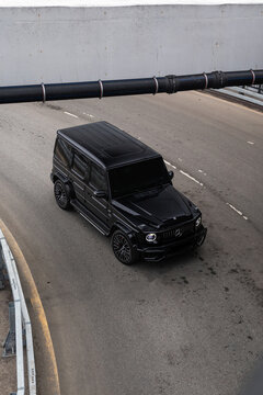 Black Mercedes-Benz G-Class AMG in urban city setting on asphalt road. Luxury SUV with iconic design, powerful presence, and premium styling. Concept of prestige, status, performance and modern