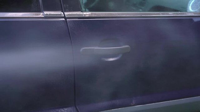 Washing handle door of car with pressure washer outdoors. High pressure car wash. Car wash