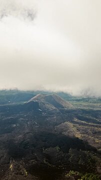 Aerial dolly hyperlapse of clouds misting over Paricutin volcano surrounded by lava fields and smoke