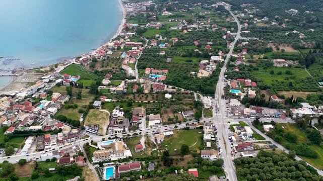 Aerial Drone View Of Roda Village Coastline And Beach In North Corfu Greece Showing Hotels Swimming Pools Main Road And Lush Green Olive Groves During A Beautiful Summer Day