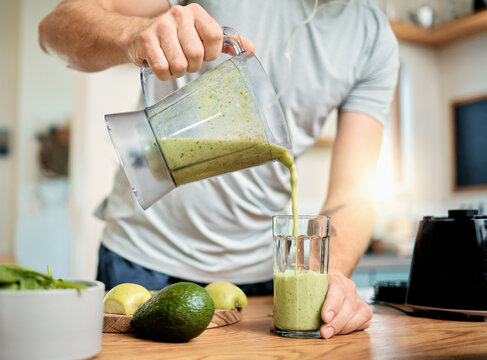 Hands, man and pour green smoothie in home for breakfast shake, health benefits and nutrition. Fruit, person and glass with nutrient beverage in blender for detox drink, healthy diet and weight loss