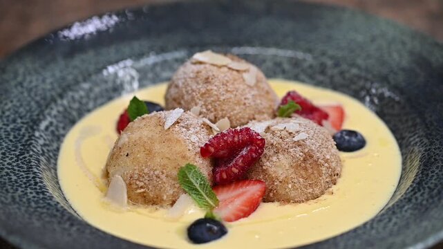 Traditional Czech fruit dumplings with fresh fruit, breadcrumbs, and vanilla sauce. Close-up of sweet homemade dessert, perfect for Czech cuisine, comfort food, and dessert photography concepts.