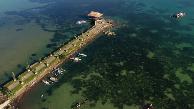 Aerial angled approach of long pier and shallow coastal waters in Bohol, drone, tilt up to city landscape