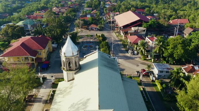Dauis Church rooftop and coastal town streets in sunny Bohol Philippines, drone dolly reveal back to front