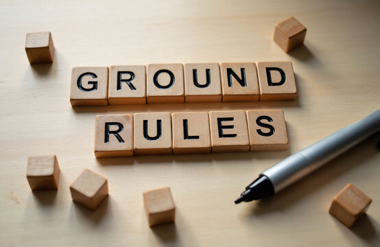 Wooden blocks spell ground rules on a table. A marker pen lies nearby. This represents guidelines for order and structure. Define what is acceptable.